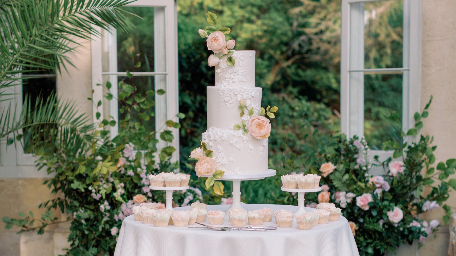 white iced wedding cake with royal iced Applique floral embellishments and soft pink sugar flowers at Syon Park. luxury wedding cake surrey